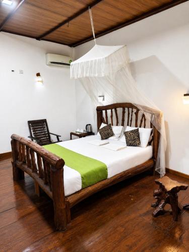 a bedroom with a wooden bed with a green blanket at Sigiri Lion Lodge in Sigiriya