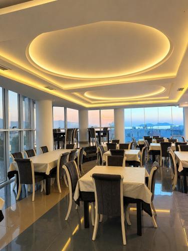 a restaurant with tables and chairs and windows at Hotel Albsin in Vlorë