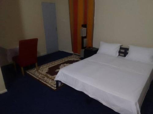 a bedroom with a white bed and a red chair at Paradise maison d'hôte in Nouakchott