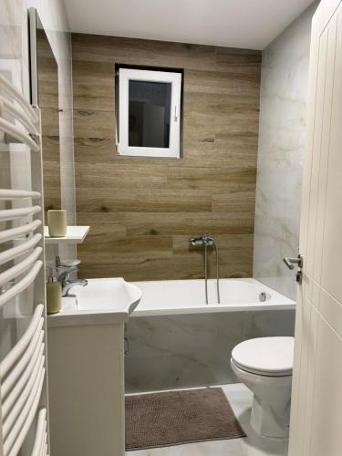 a bathroom with a tub and a toilet and a sink at Apartman Laki in Bijeljina