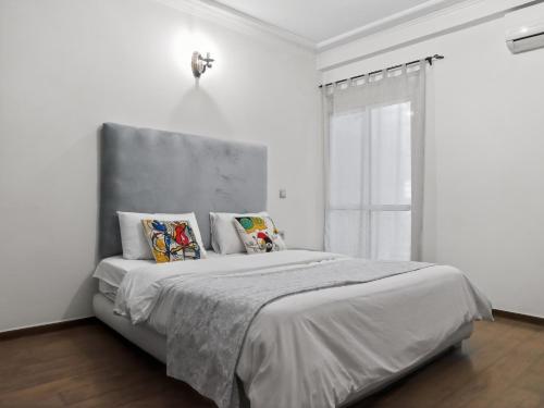 a white bedroom with a large bed with pillows at Atlas - Appartement moderne in Fez