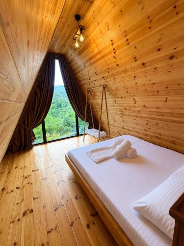 a bed in a wooden room with a large window at Rozafa Sunset in Shkodër