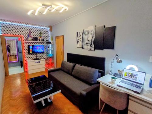 a living room with a couch and a desk with a laptop at APARTAMENT VENGE -CAŁE MIESZKANIE 46m2 NA WYŁĄCZNOŚĆ - Z JEDNĄ SYPIALNIĄ I JEDNYM SYPIALNO-SALONEM -3 PIĘTRO BEZ WINDY- REZERWACJA BEZ KARTY KREDYTOWEJ-KLIMATYZACJA-KINO DOMOWE-PROJEKTOR-100"-NETFLIX-BEZPŁATNY PARKING PUBLICZNY NA MONITOROWANYM PODWÓRZU in Wrocław