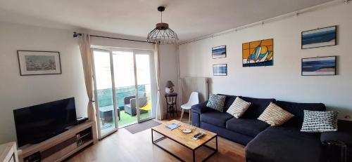 a living room with a blue couch and a tv at Le vitrail d'Arcachon - Appt Spacieux Terrasse Ménage draps inclus in Arcachon