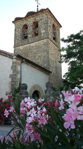 a church with a clock tower with pink flowers at Casas de la Fuente in Brieva
