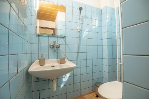 a blue tiled bathroom with a sink and a toilet at Chalupa U lesa in Karlova Studánka