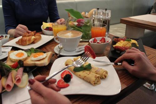 a group of people sitting at a table with breakfast foods at Danubia Gate Hotel in Bratislava
