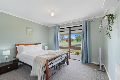 a bedroom with a bed and a large window at Wildlife, Waves Getaway in Acton Park