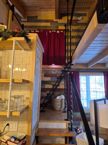 a staircase in a tiny house with a red curtain at Cozy Christmas Cabin in North Pole