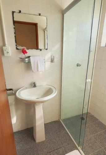 a bathroom with a sink and a glass shower at Pousada Tribo Ubatuba in Ubatuba