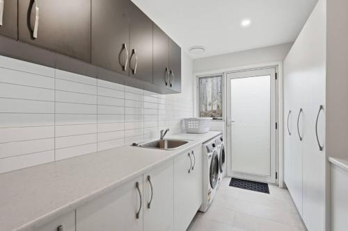 a white kitchen with a sink and a dishwasher at Stylish Rosetta Waterview Stay in Rosetta