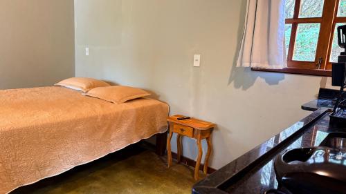 a bedroom with a bed and a table and a window at Vila Clara do Capão in Vale do Capao