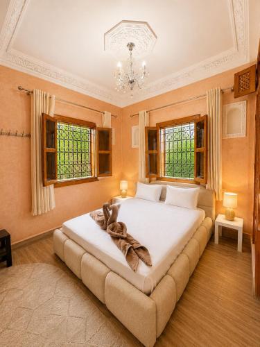 a bedroom with a large white bed in a room with windows at Villa lumina , Marrakech in Oulad Mazoug
