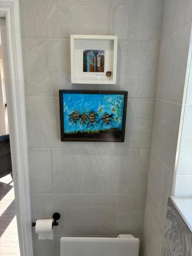 a bathroom with a tv on the wall above a toilet at Griffin Lodge in Warwick