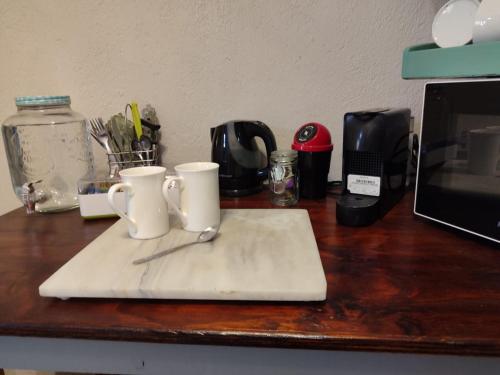 a counter with two coffee cups on a cutting board at Serendipity Garden Studio Gateway to Kruger and Panorama Route in Kampersrus AH