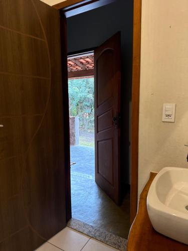 a bathroom with a door and a sink and a toilet at Vila Clara do Capão in Vale do Capao