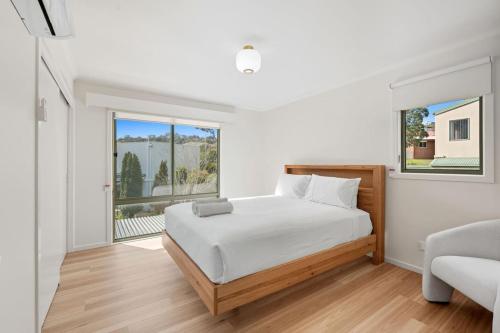 a white bedroom with a bed and a window at Riverview Townhouse Retreat in Lindisfarne
