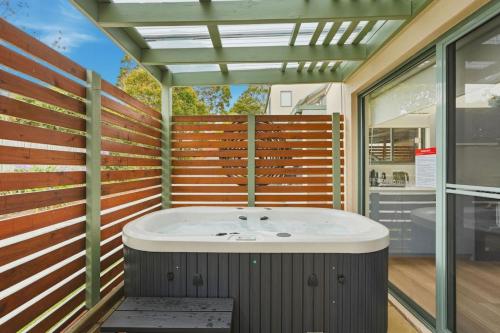 a bathroom with a tub and a wooden wall at Riverview Townhouse Retreat in Lindisfarne