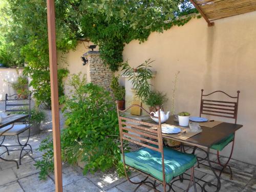 a patio with a table and chairs with plants at Clos des Lavandes - Chambres et Suites de charme climatisées-Luberon in Lacoste
