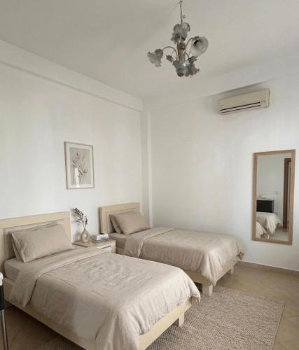 a bedroom with two beds and a mirror and a chandelier at Tirana Terminal Stay in Tirana