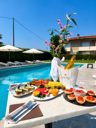 a table with plates of food next to a pool at Hotel Venezia Park - ENJOY HOLIDAY in Colà di Lazise