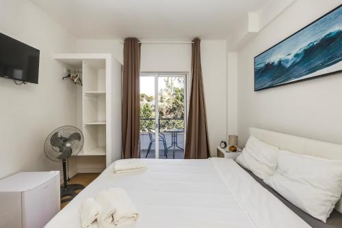 a white bedroom with a bed and a window at Maison Azur Oeiras Beach in Oeiras