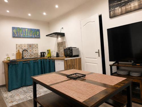 a kitchen with a table and a television in a room at Le cocondor - Design soigné et Parking facile in Montréjeau