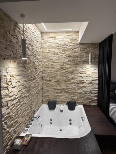 a bath tub in a room with a stone wall at Apartmani Harmonija in Vrbas