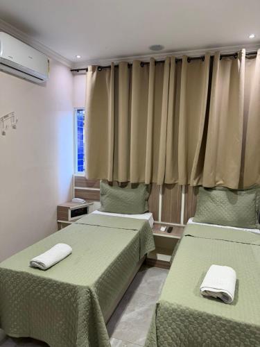 a bedroom with two beds with green sheets and a window at Hotel Prime Tatuapé - Próximo ao Metrô Belém - Café da Manhã Incluso e Estacionamento Econômico no Local in São Paulo