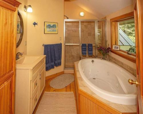a bathroom with a large tub and a shower at Authentic VT Chalet, Hot tub, Fire pit, Mt Snow in Dover