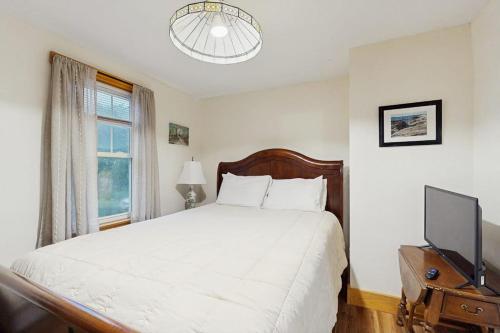 a bedroom with a white bed and a television at 2-story apartment steps from the harbor & downtown in Boothbay Harbor