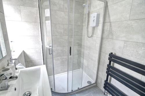 a shower with a glass door next to a sink at Kingspark Apartment Apartment in Glasgow