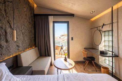 a hotel room with a bed and a table and a window at D&C Premium Suites in Pefkochori