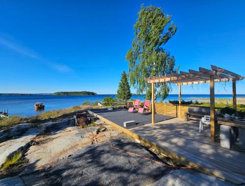 a pavilion with a picnic table and benches next to the water at Paradise cottage w sea view in Brännöviken 5, Lögdeå in Lögdeå