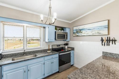 a kitchen with blue cabinets and a sink at Escape OBX in Kitty Hawk