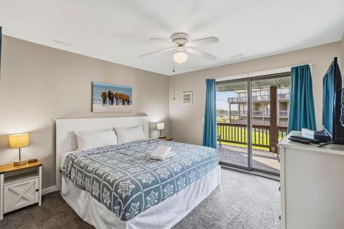 a bedroom with a bed and a tv and a balcony at Escape OBX in Kitty Hawk