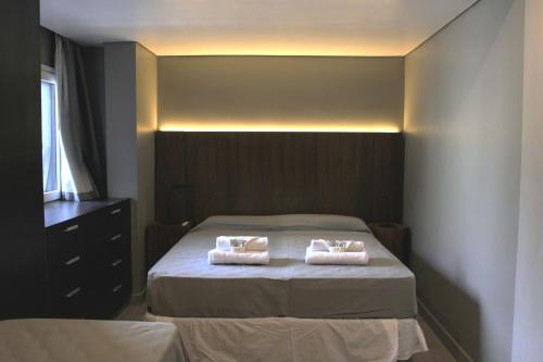 a bedroom with a bed with two towels on it at Stream Suites Pinamar in Ostende