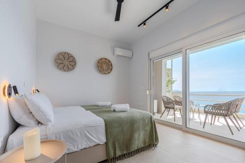 a white bedroom with a bed and a balcony at East of Preveli Seafront Villas by TheCreteEscape in Kerames