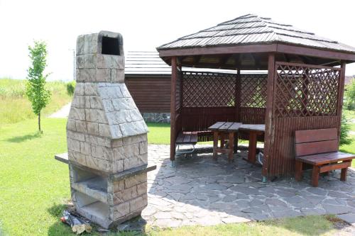 a wooden gazebo with a table and a stone fireplace at Tatralandia-Liptov Chatky in Liptovský Mikuláš