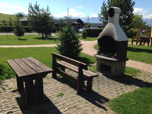a picnic table and a bench next to a fireplace at Tatralandia-Liptov Chatky in Liptovský Mikuláš