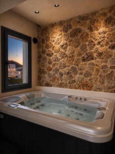 a large tub in a room with a stone wall at Ethos Suites in Agios Prokopios
