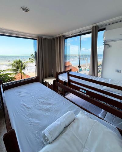 two beds in a bedroom with a view of the beach at Maraga Beach Hostel in Maragogi