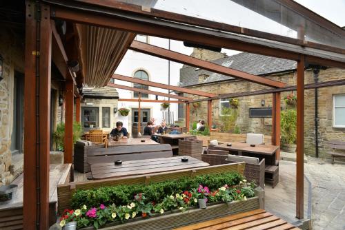 an outdoor patio with tables and benches and flowers at The Woolly Sheep Inn in Skipton