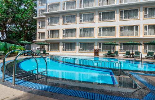 a swimming pool in front of a building at Verano Hotel & Spa Arpora Goa in Arpora