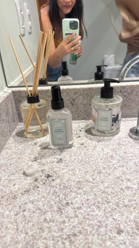 a woman taking a picture of herself in a bathroom mirror at Apartamento 313 Bobz Concept in Cajueiro