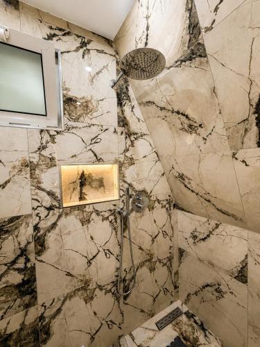a bathroom with a television and a marble wall at Rozafa Sunset in Shkodër
