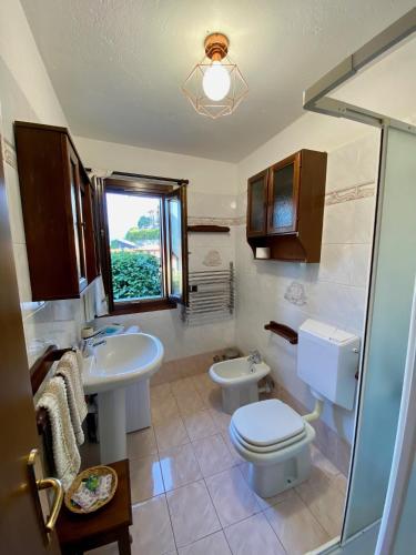 a bathroom with a toilet and a sink and a window at Castello Cottage in Argegno