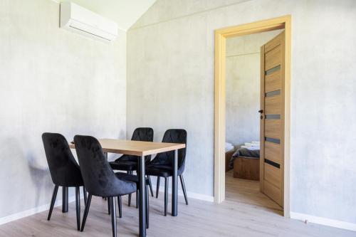 a dining room with a table and black chairs at Domki u Basi - 250m do Plaży - Idealne dla Rodzin in Karwia