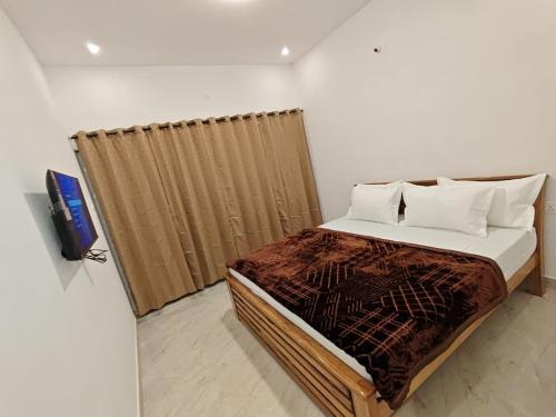 a bedroom with a bed with a curtain and a tv at Mithra Cottages individual Villa in Ooty