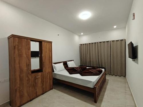 a bedroom with a bed with a wooden cabinet at Mithra Cottages individual Villa in Ooty
